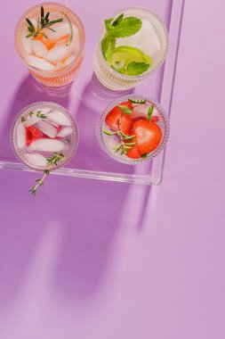 Yaz ferahlatıcı içecekler mor arka planda plastik bir tepside, üst manzara