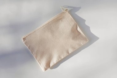 Tuvalin kozmetik çantası beyaz masanın üzerindeki doğal ışıkla modellenir.