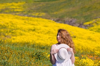 Baharın tadını çıkaran bir kadın Parlak sarı çiçeklerle dolu çayırların arasında.
