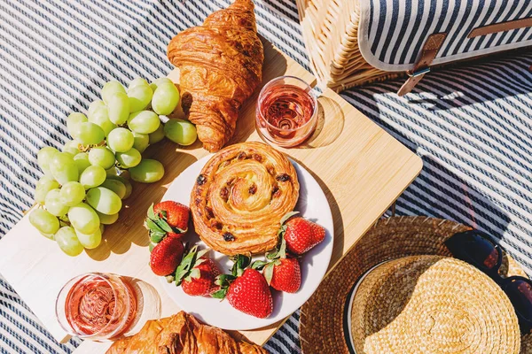 stock image Fruits, croissant and rose wine on the picnic blanket on sunny summer day, top view