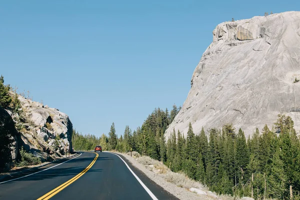 Δρόμος Διασχίζει Βουνά Ένα Κόκκινο Αυτοκίνητο Απόσταση Μια Ηλιόλουστη Μέρα — Φωτογραφία Αρχείου