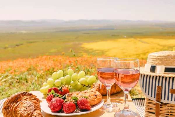 玫瑰酒 羊角面包和草莓放在小桌子上 野餐在美丽的春天草地上 野花盛开 — 图库照片