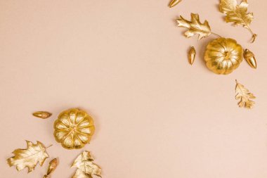 Metin için boş alanı olan altın renklerde dekore et. Altın boyalı yapraklar, balkabakları ve meşe palamutları, sonbahar kompozisyonu