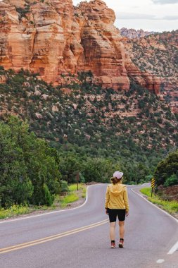 Zion Ulusal Parkı 'nda arabasız duran kadın, arkadan manzaralı.