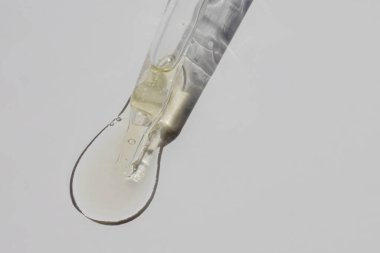 Serum, yağ veya vitamin esanslı pipete yakın plan beyaz zemin üzerinde izole edilmiş, sert gölgeli doğal güneş ışığı