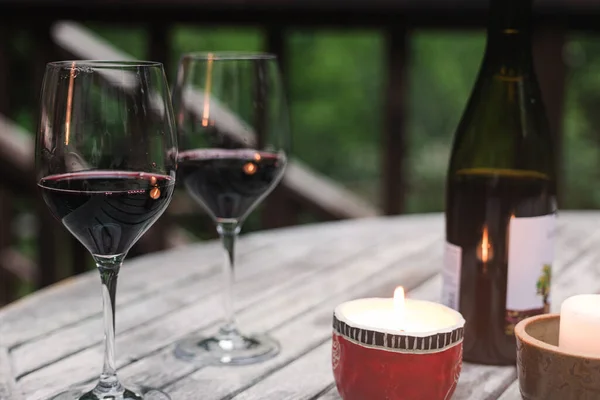 两杯红酒倒立在木桌上 点着蜡烛 散发着浪漫的气氛 — 图库照片