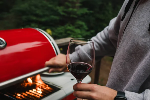 在温暖的夏夜 男人们在后院烧烤的时候举着一杯红酒的特写镜头 — 图库照片