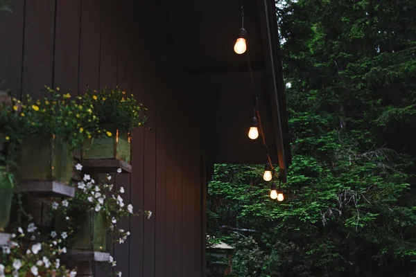 夏日夜晚 舒适的木制小木屋庭院 装饰着温暖的轻盈的花环 — 图库照片#
