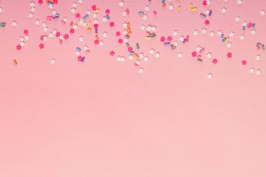Fotokopi alanı ve parti arkaplanı olan pembe arkaplan üzerine renkli yıldız şekilli şeker serpintileri
