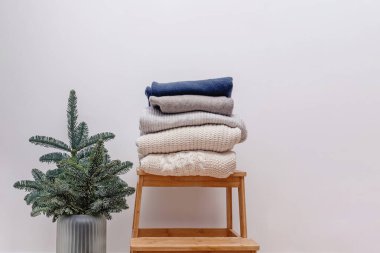 Tahta tabure ve köknar dallarında örgü süveter olan minimalist kış mevsimi kompozisyonu.