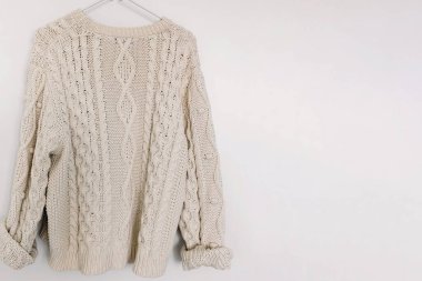 Beyaz duvarın üzerindeki askıda örülmüş örgü süveter.