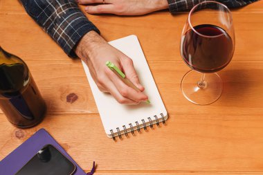 Not defterine bir bardak şarap yazan adam alkol miktarını takip ediyor ya da şarap hakkında not tutuyor..