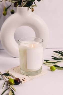 Boş etiketli yanan mum, zeytin dalları ve zeytinler