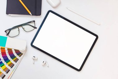 Renk örnekleriyle grafiksel tasarımcı çalışma yeri ve boş ekranlı tablet, maket, üst görünüm
