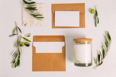 Boş kağıt kart, boş alan ve mum. Zeytin dallarıyla düz bir kompozisyon. Damgalama, modelleme, metin için yer