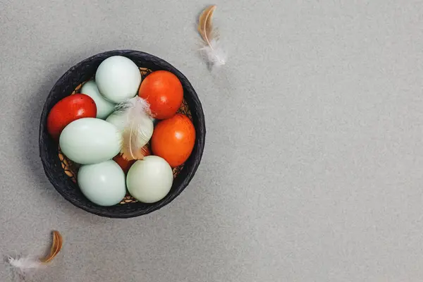 Sepette mavi ve kırmızı renkli yumurtalar ve kuş tüyleri üst görünüm, Paskalya kompozisyonu