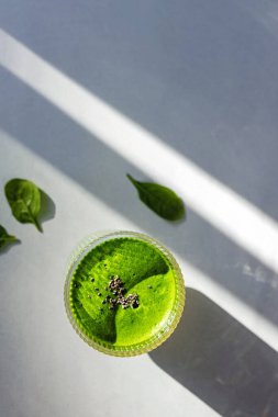 Üzerinde chia tohumları olan flütlü bardakta yeşil smoothie, sağlıklı bir sabah içeceği, üst manzara.