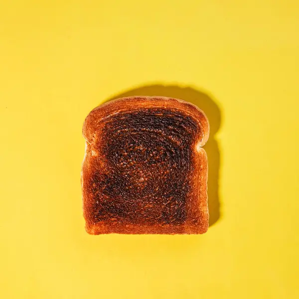 Square bread slice, burned toast isolated on the yellow background