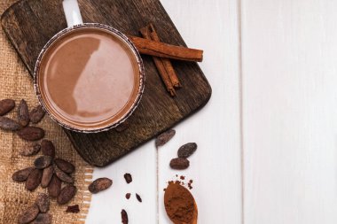 Beyaz ahşap masada bir fincan sıcak çikolata ve kakao çekirdeği.