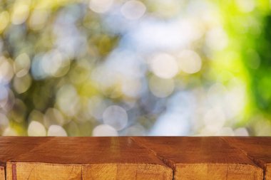Arka planda yeşil bokeh, ürün için yer, yaz şablonu olan Rustik ahşap ekran masası