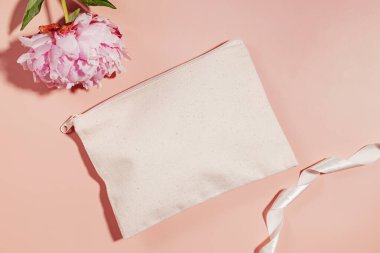 Makyaj çantası maketi ve pembe fonda pembe şakayık, üst manzara.