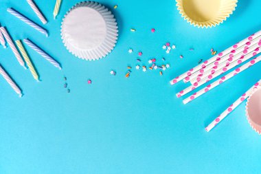 Kek kapları, mumlar ve konfetiler mavi arka planda, parti hazırlığı.