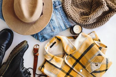 Sonbahar modasının düz yatışı bej şapka, kot pantolon, örgü atkı ve sarı ekose gömlek de dahil olmak üzere.