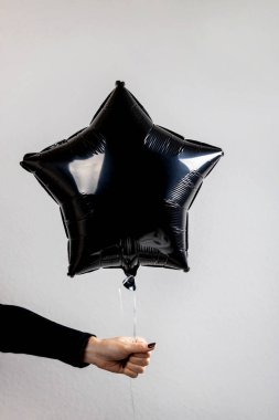 Kutlama sırasında el ele tutuşan siyah yıldız şekilli balon minimalist gri bir arkaplan karşısında