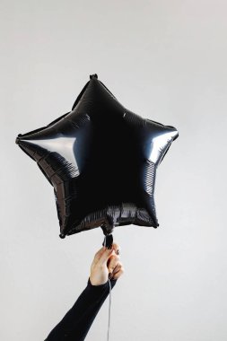 Kutlama sırasında el ele tutuşan siyah yıldız şekilli balon minimalist gri bir arkaplan karşısında