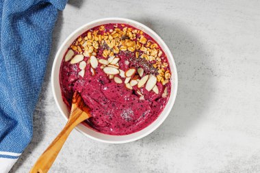 Parlak ve kremalı meyve püresi. Üstünde granola ve badem var.