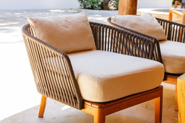 Güneş ışığı altında doğal elementlerle dolu karşılama bahçesine yerleştirilmiş rahat şezlonglar.