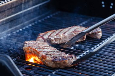 Sıcak ızgarada cızırdayan iki lezzetli bifteğin yakın çekim görüntüsü