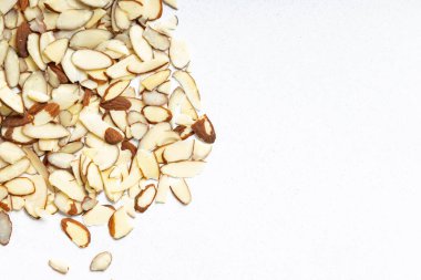 Dilimlenmiş bademler bir mutfak ortamında, ışık yüzeyine saçılmış.