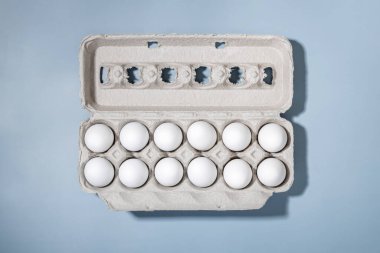 Mavi arka planda bir kutuda taze beyaz yumurta, üst manzara.