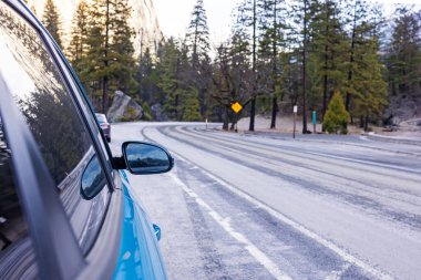 Yosemite Ulusal Parkı yakınlarındaki bir orman bölgesinde kışın dolambaçlı yol boyunca manzaralı sürüş