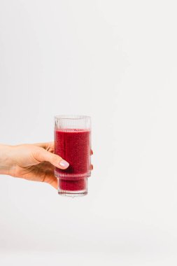 Bir el, arka planda canlı bir dut kokteyli ile dolu bir bardağı tutar.