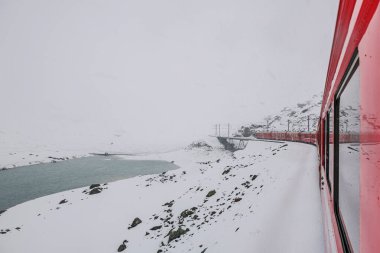 Bir kırmızı tren karlı bir arazide seyahat eder, karlı bir dağ yolunda.