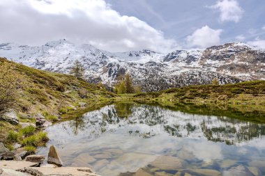 İlkbaharda karla kaplı dağlar sakin gölün aynası.