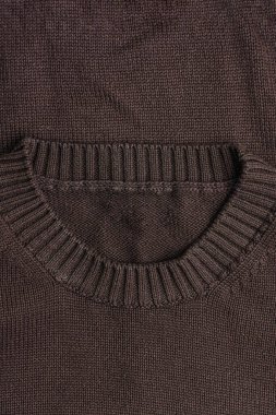 Yakından tırtıklı yakalı ve cebinde kahverengi bir kazak.