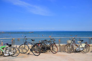 Grado, İtalya - 20 Temmuz 2019: Sahil kenarındaki gezinti alanında parketmiş bisikletler