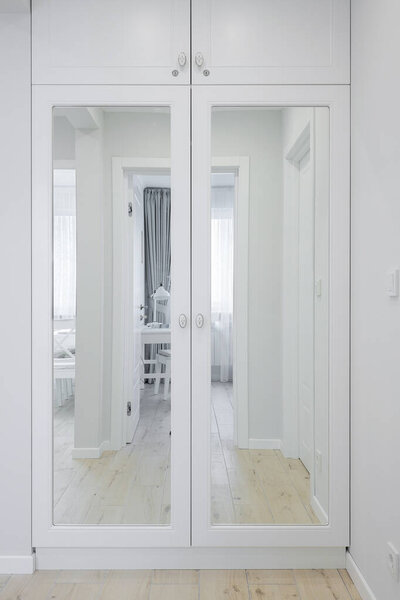 White wooden cabinet with a mirror in the hallway interior