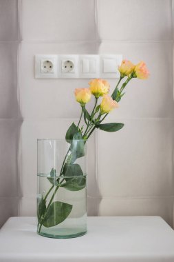 İçerideki yatak odasındaki bir masanın üstünde vazoda gül çiçekleri.