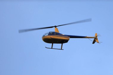Helikopter Robinson R44 mavi gökyüzünde uçuyor