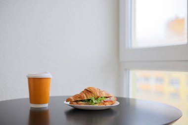 Sandviç ve kahve masanın üzerinde plastik bardakta.