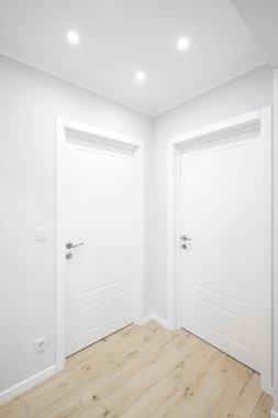 Koridorun içinde beyaz iç kapılar var.
