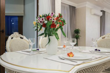 Beyaz tabaklar ve şarap kadehleriyle ayrılmış masa.