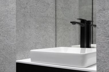 Banyoda seramik lavabo ve ayna olan musluk.