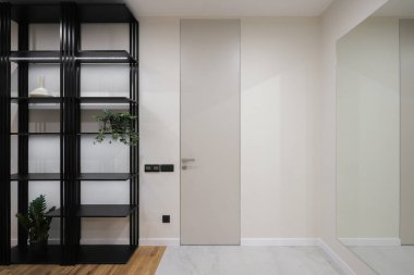 Koridorda siyah raf ünitesi var.