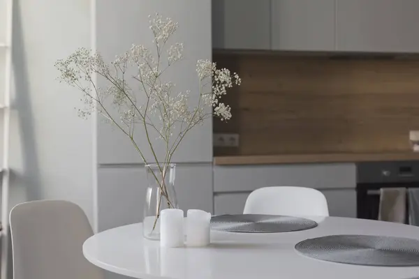 在木制和灰色丑闻的厨房前餐厅的白色圆桌 典雅的北欧风格 玻璃花瓶中的花朵和室内装饰 — 图库照片