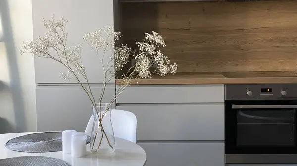 在木制和灰色丑闻的厨房前餐厅的白色圆桌 典雅的北欧风格 玻璃花瓶中的花朵和室内装饰 — 图库照片